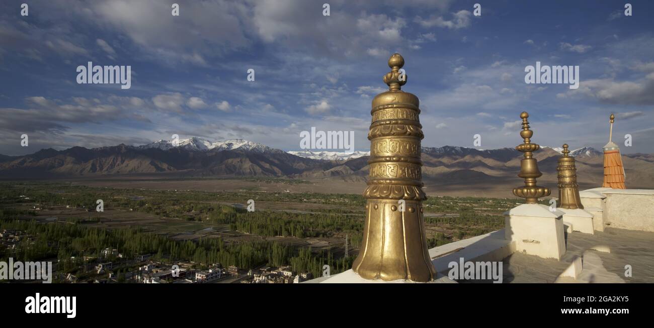 View from the rooftop of the Thikse Moanastery with its large golden finials, overlooking the village and the Indus Valley, through the Himalayan M... Stock Photo
