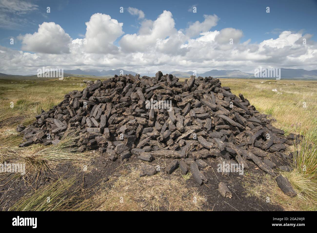 Turf cut and stacked in a pile of peat bricks along the Bog Road (Bothar na Scrathog) in Connemara; Carraroe, County Galway, Ireland Stock Photo