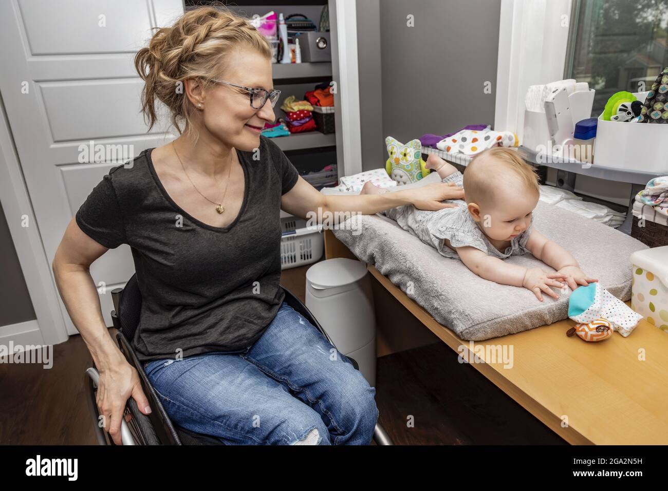 A mother in a wheelchair rubbing her baby's back after a diaper change