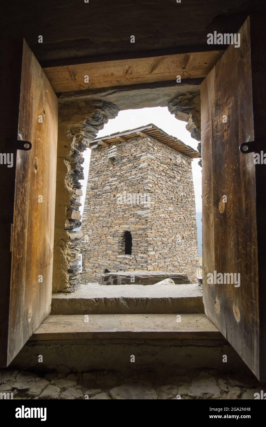 Close-up of a Keselo tower window with a view out to a neighboring stone tower house in Omalo in the Tusheti National Park; Omalo, Kakheti, Georgia Stock Photo