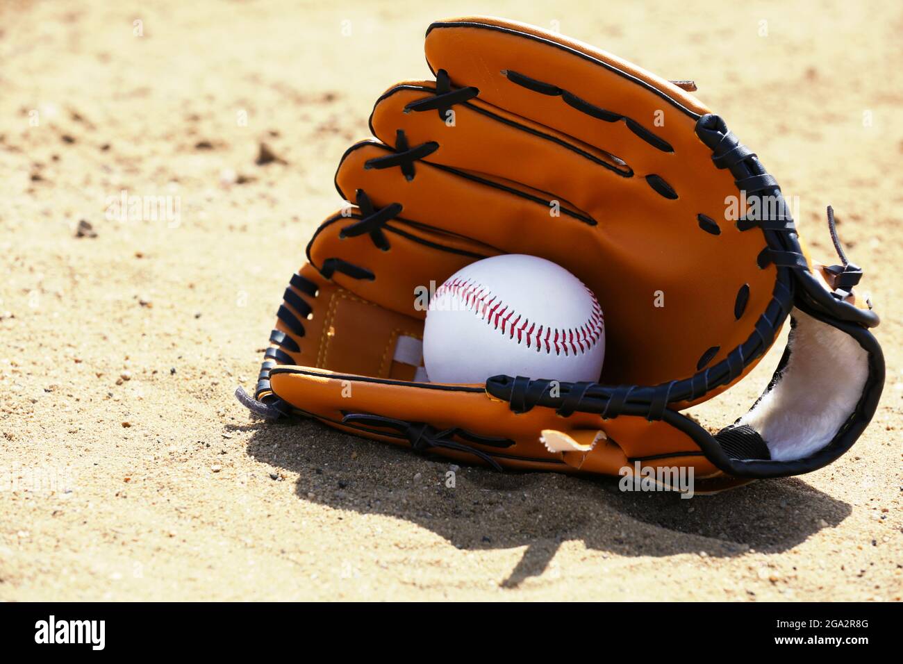 Baseball ball and glove on sand Stock Photo Alamy