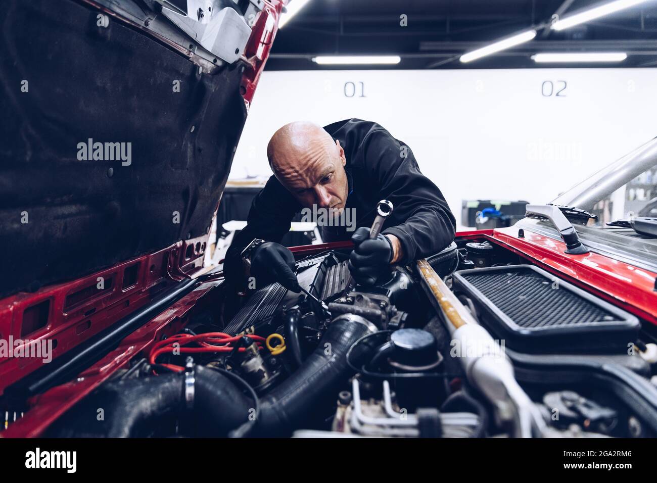 Man car service worker fixing or regulating engine Stock Photo - Alamy