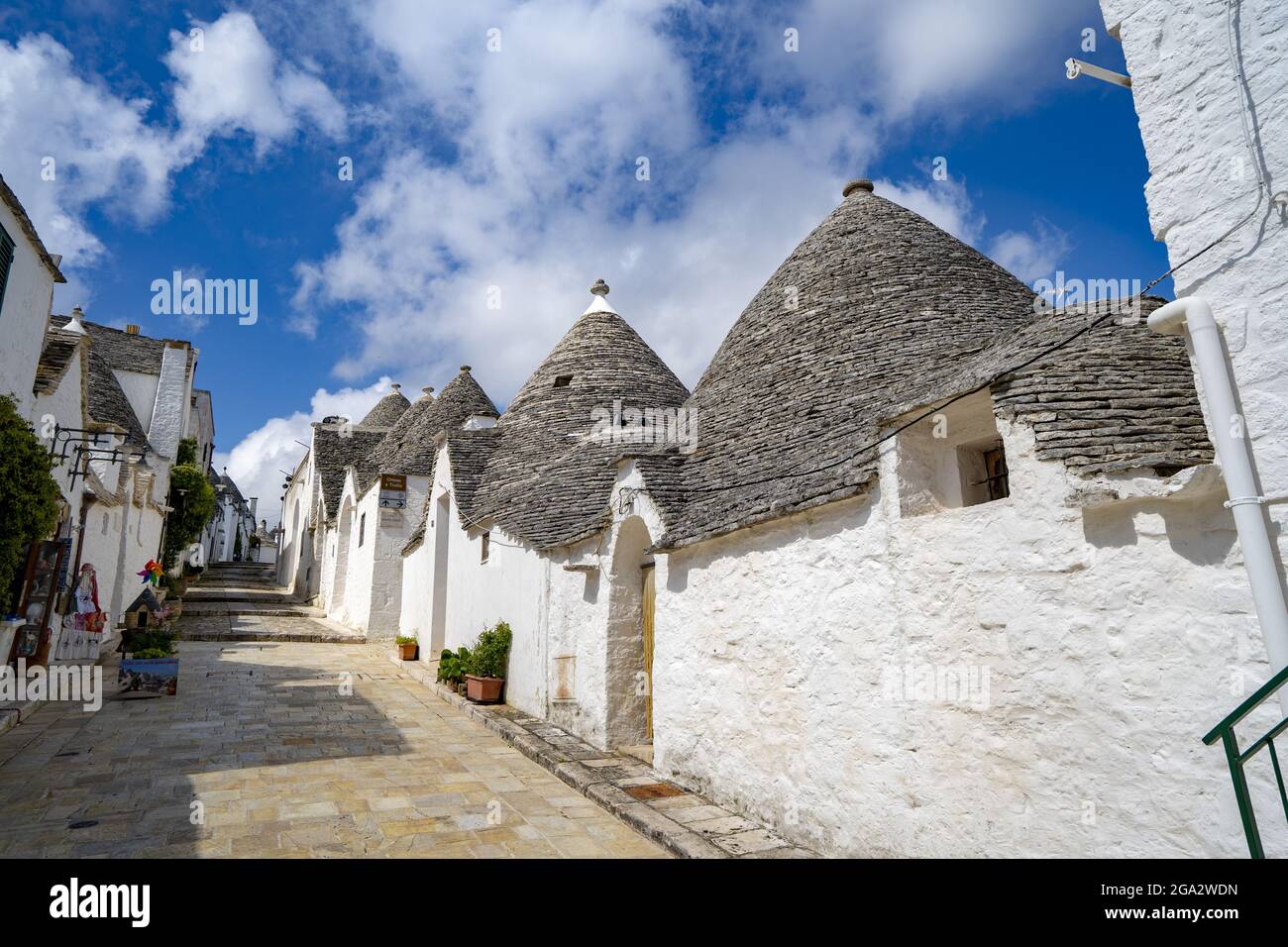 Street scene with a row of traditional Apulian round stone Trulli houses in the town of Alberobello; Alberobello, Puglia, Italy Stock Photo