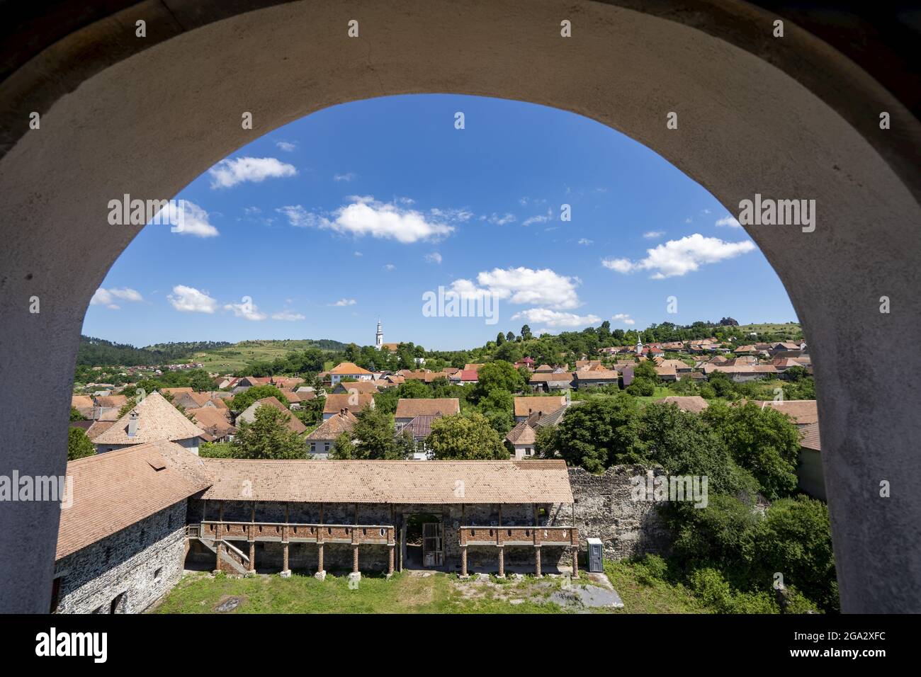 View of the town and the Cetatea Bethlen Medieval Castle of Racos through an archway; Racos, Transylvania, Romania Stock Photo