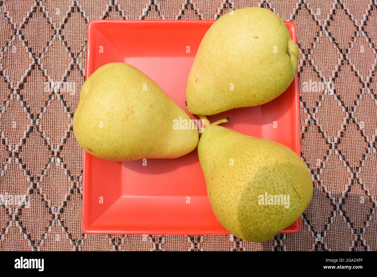 Top view of Pear fruits on red plate background. Sweet soft delicious fruits Stock Photo