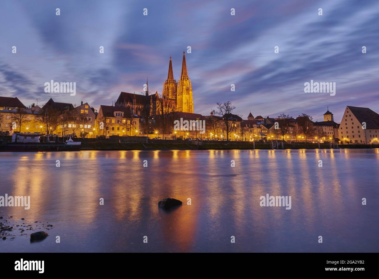 Outlook over the Danube River with the Gothic St Peter's Cathedral from the Marc-Aurel-shore in the Old Town of Regensburg at dusk Stock Photo