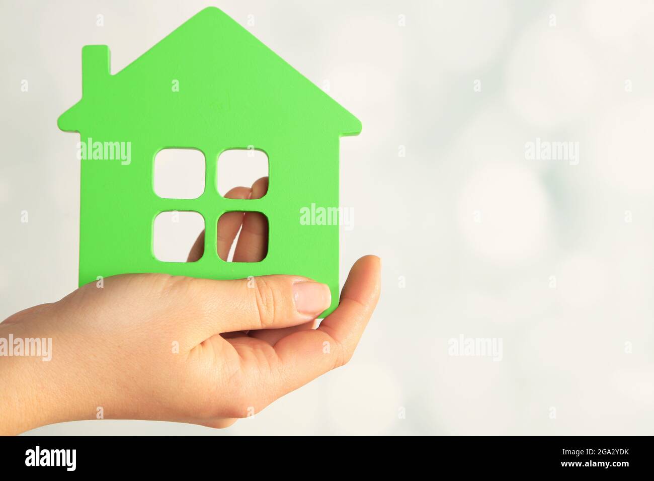 Female hand with model of house on blurred background Stock Photo - Alamy