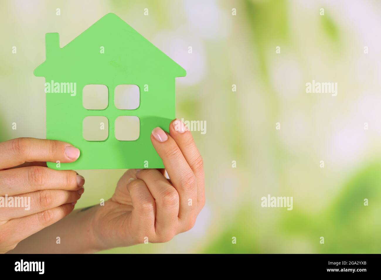 Female hands with model of house on blurred background Stock Photo - Alamy
