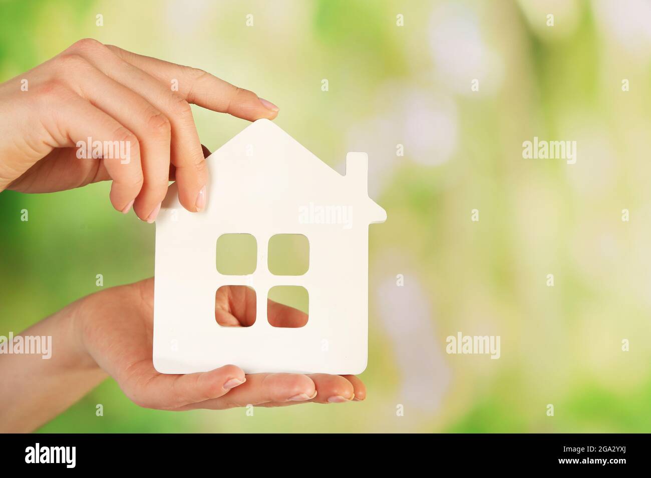 Female hands with model of house on blurred background Stock Photo - Alamy