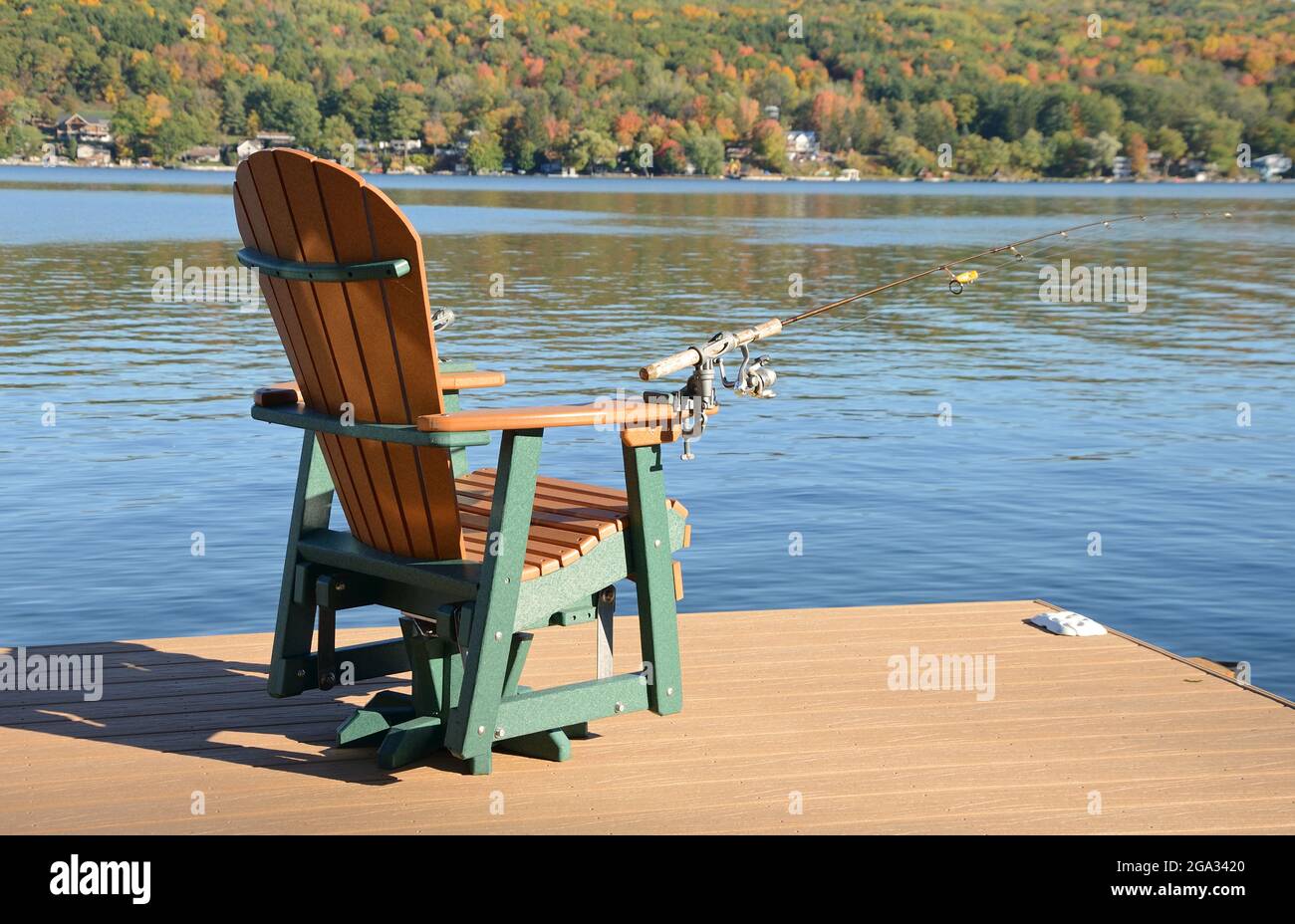 Empty chair on dock awaiting fisherman in autumn, Finger Lakes Region; New York, United States of America Stock Photo