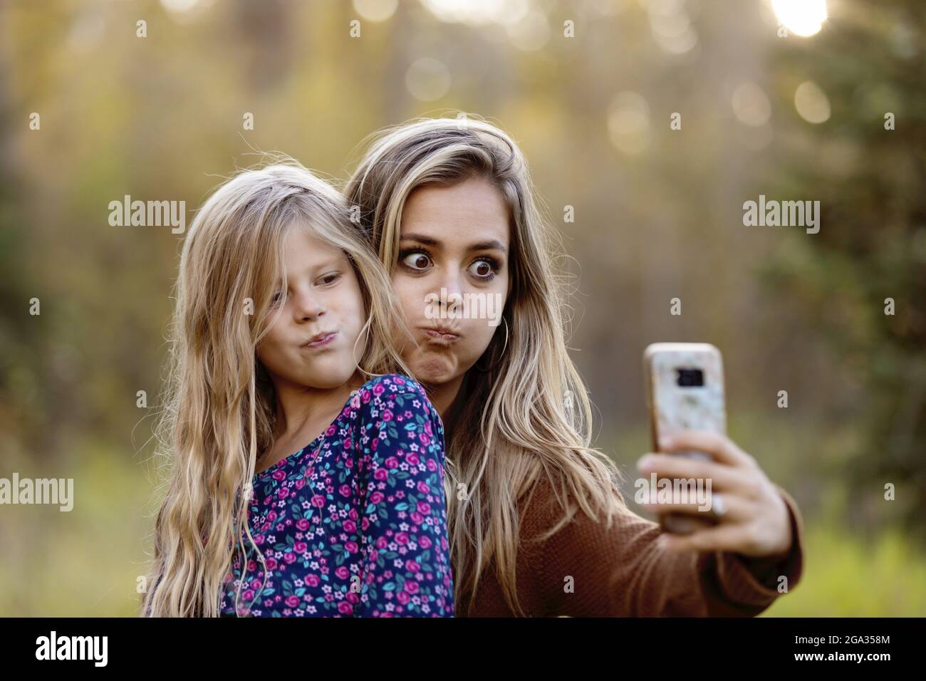 A mother spending quality time outdoors with her daughter and taking a self-portrait in a city park; Edmonton, Alberta, Canada Stock Photo