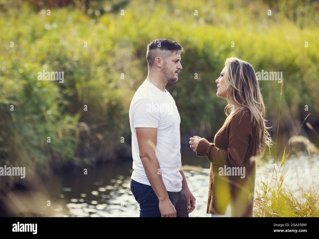 Husband and wife spending quality time together outdoors near a stream in a city park and having a serious discussion; Edmonton, Alberta, Canada Stock Photo