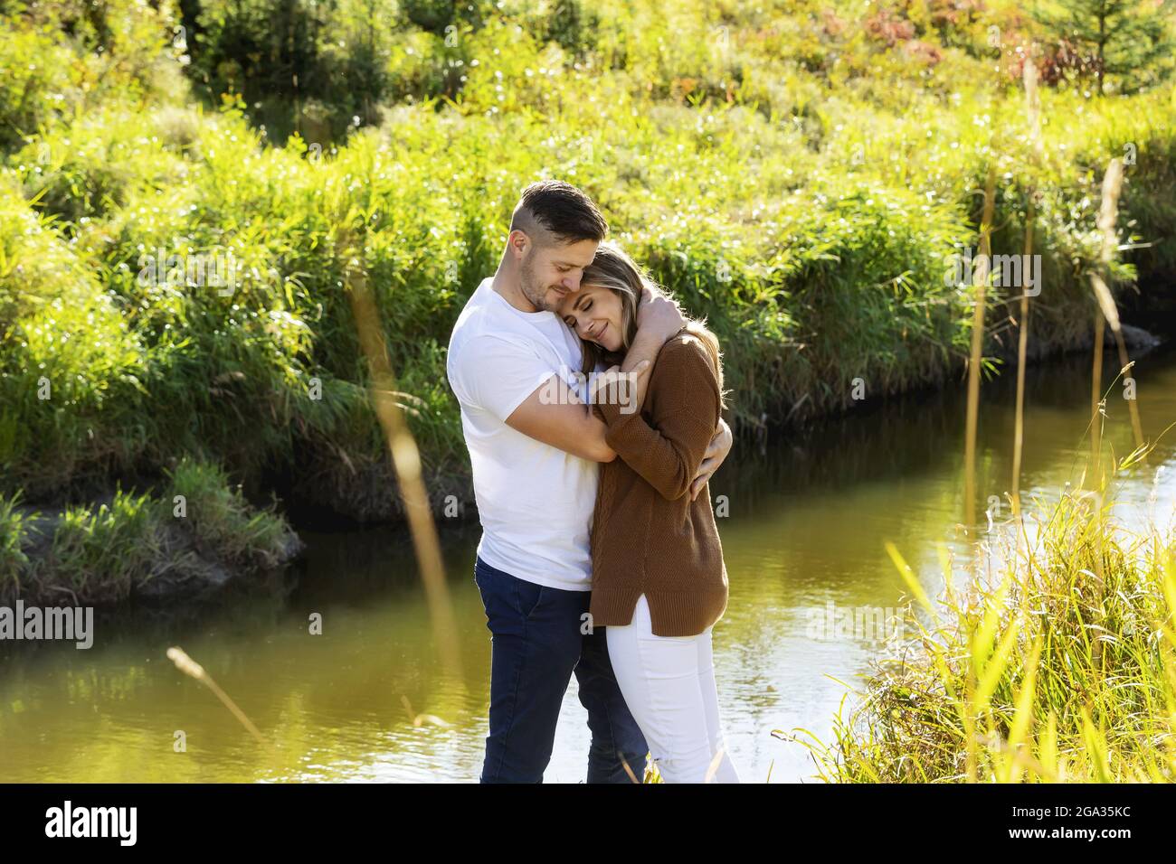 Husband and wife spending quality time together outdoors near a stream in a city park; Edmonton, Alberta, Canada Stock Photo