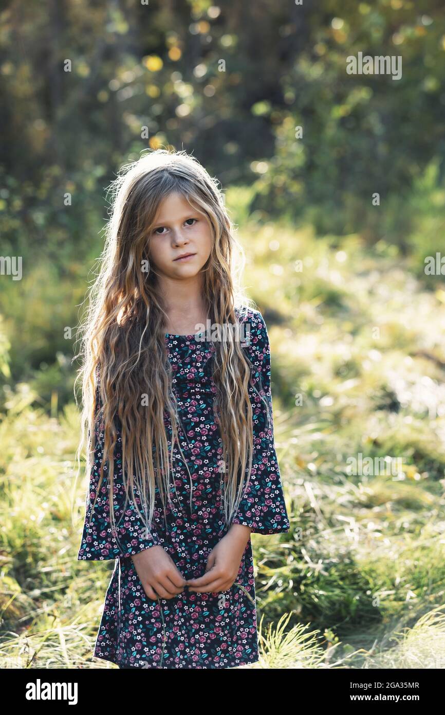 A portrait of a pretty little girl with long hair in a city park during the fall season; Edmonton, Alberta, Canada Stock Photo