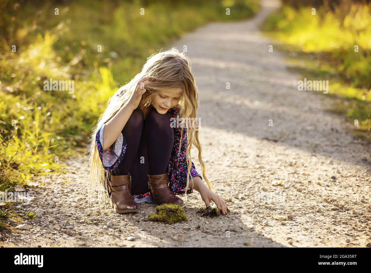 A young girl with long hair plays on a trail in a city park during the fall season; Edmonton, Alberta, Canada Stock Photo