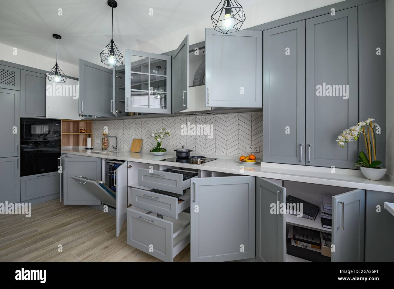 Trendy grey and white modern kitchen furniture with doors open Stock
