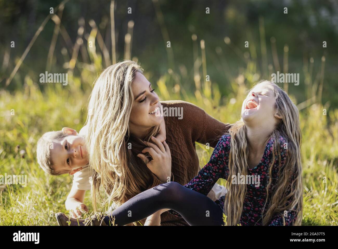 A mother and her young children spending quality time together in a city park during the fall season; Edmonton, Alberta, Canada Stock Photo