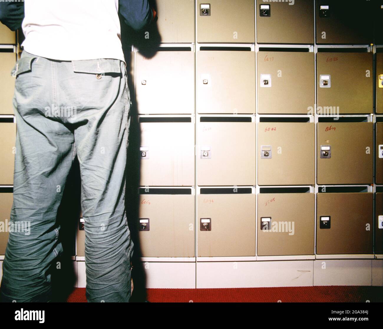 Man standing at a wall of safe deposit deposits with a key to open a