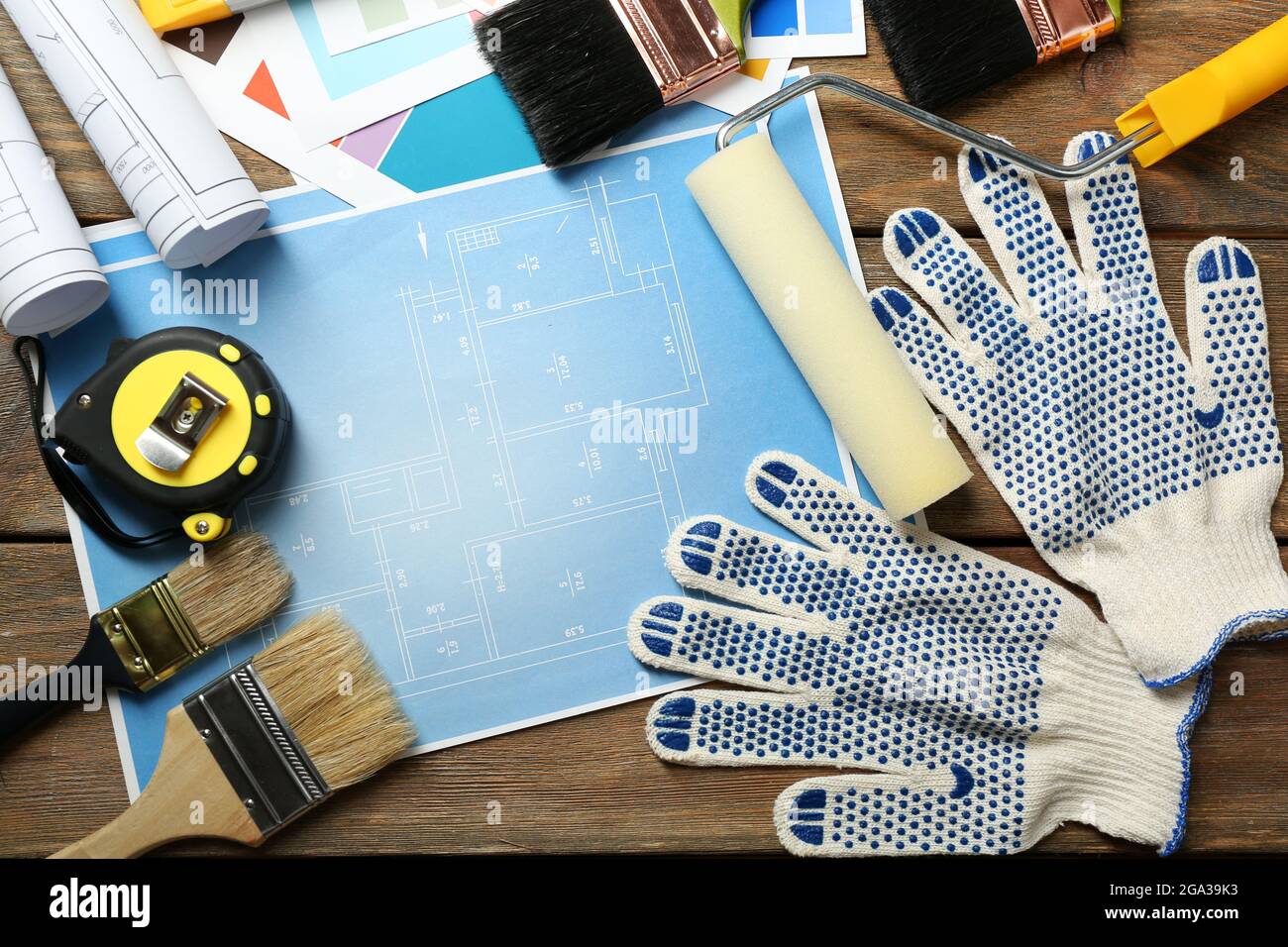 Construction instruments, plan and brushes on wooden table background ...