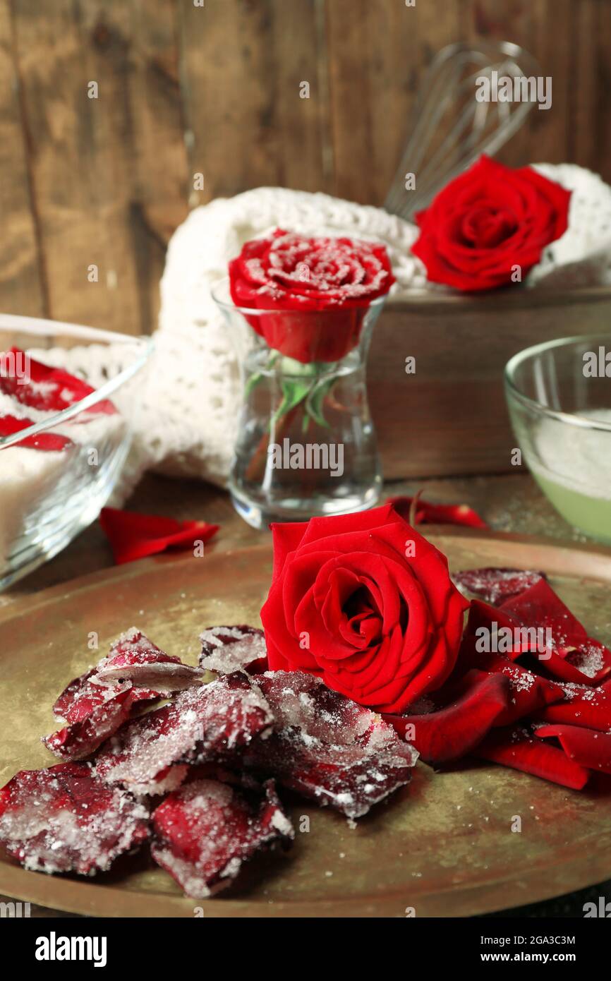 Making candied rose flower petals with egg whites and sugar, on wooden