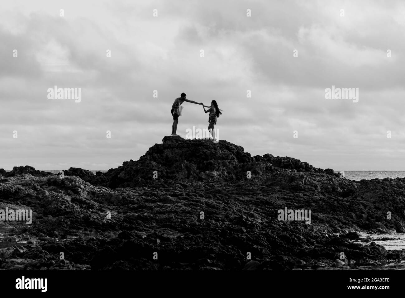 silhouette of two people on a very large rock. Ondina Beach in Salvador, Bahia, Brazil. Stock Photo