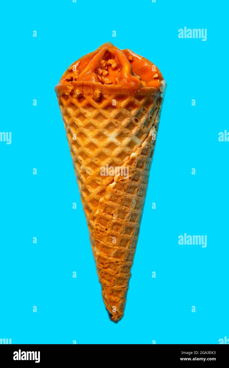 Vertical photo of caramel ice cream on light blue background. Stock Photo