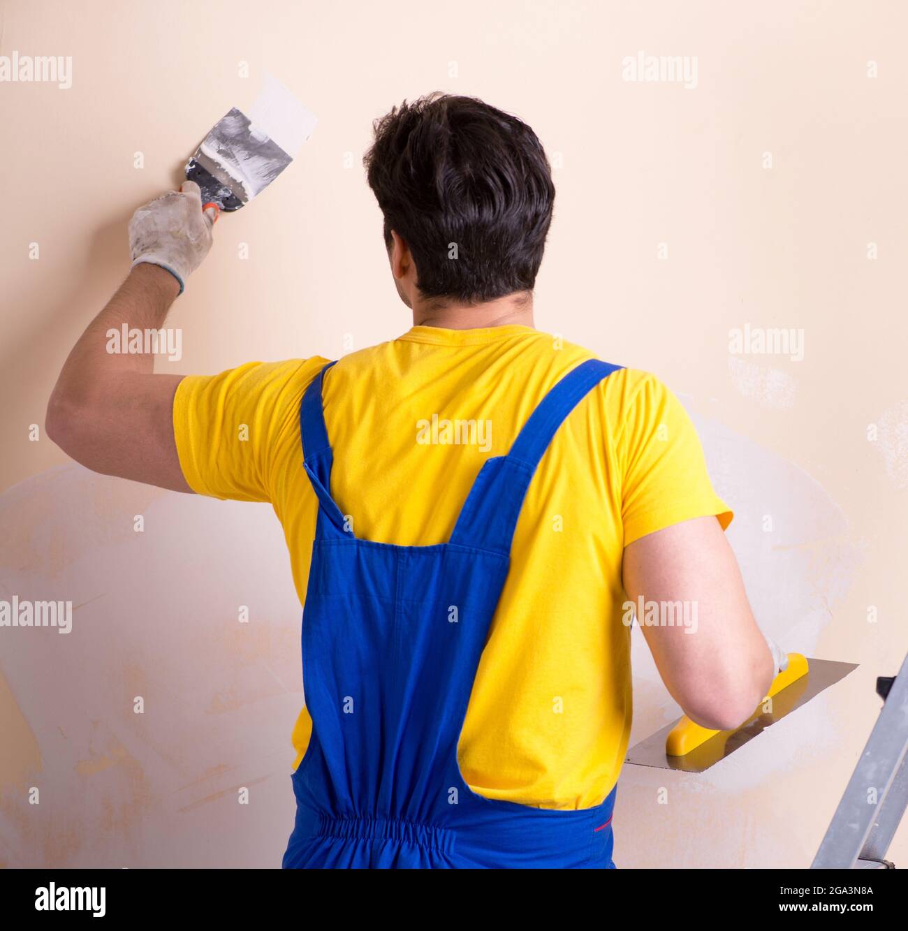 The young contractor employee applying plaster on wall Stock Photo