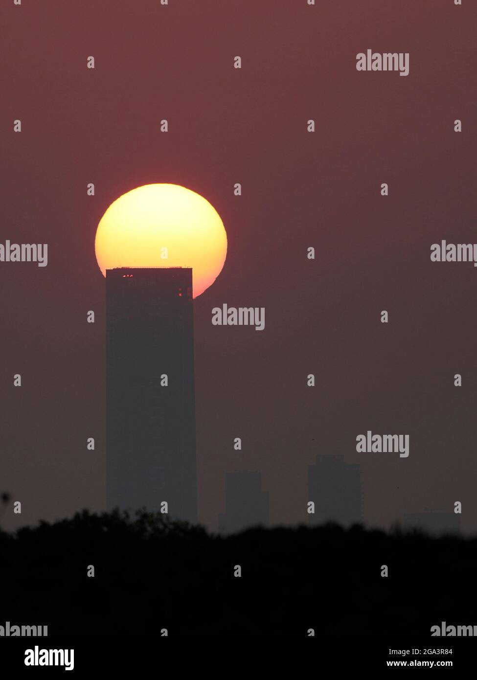 Sun setting behind high-rise tower, Shenzhen, China, view from New Territories, Hong Kong 23rd April 2021 Stock Photo