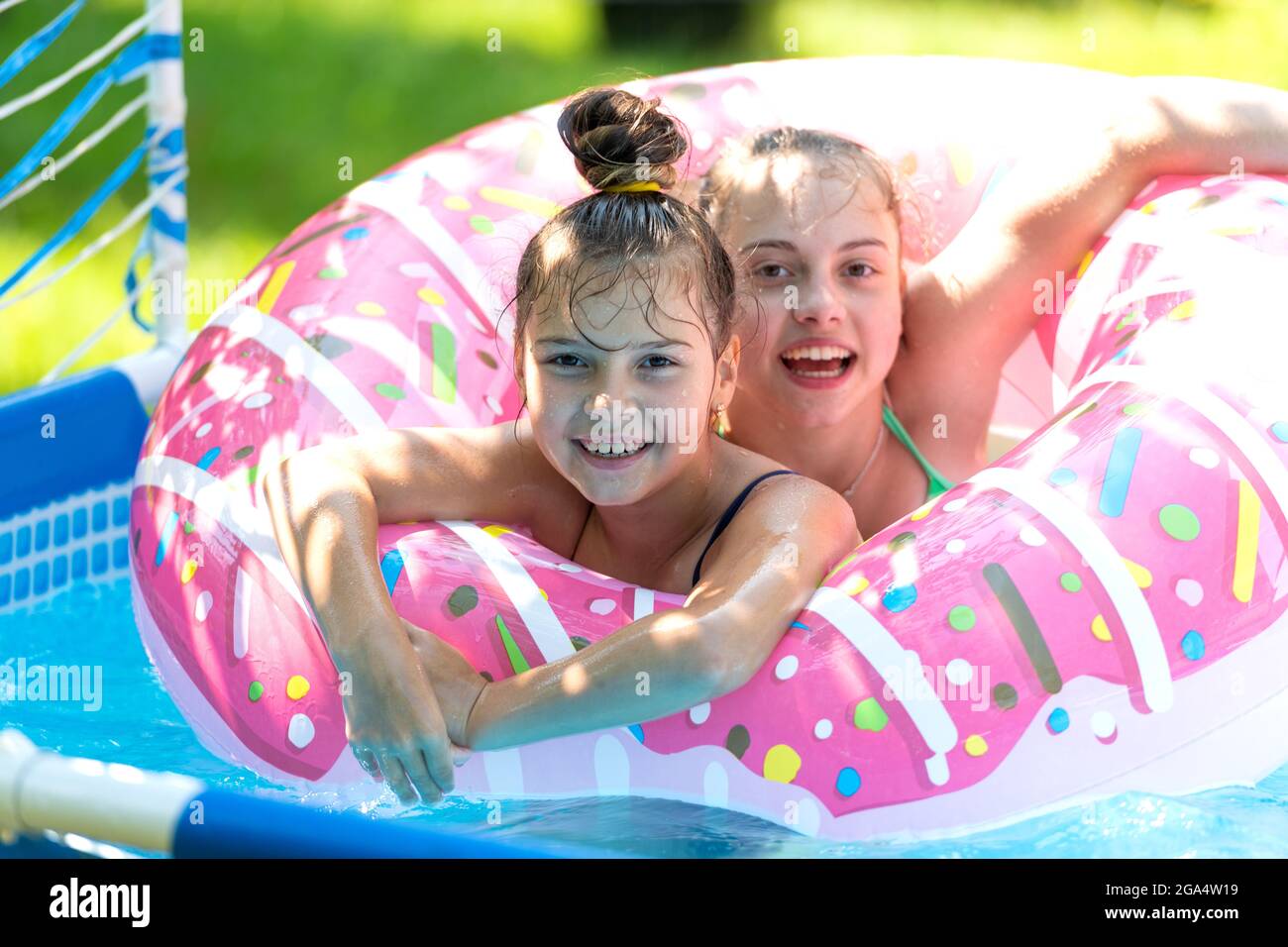 The perfect way to stay cool. Happy kids swim in donut pool float. Pool