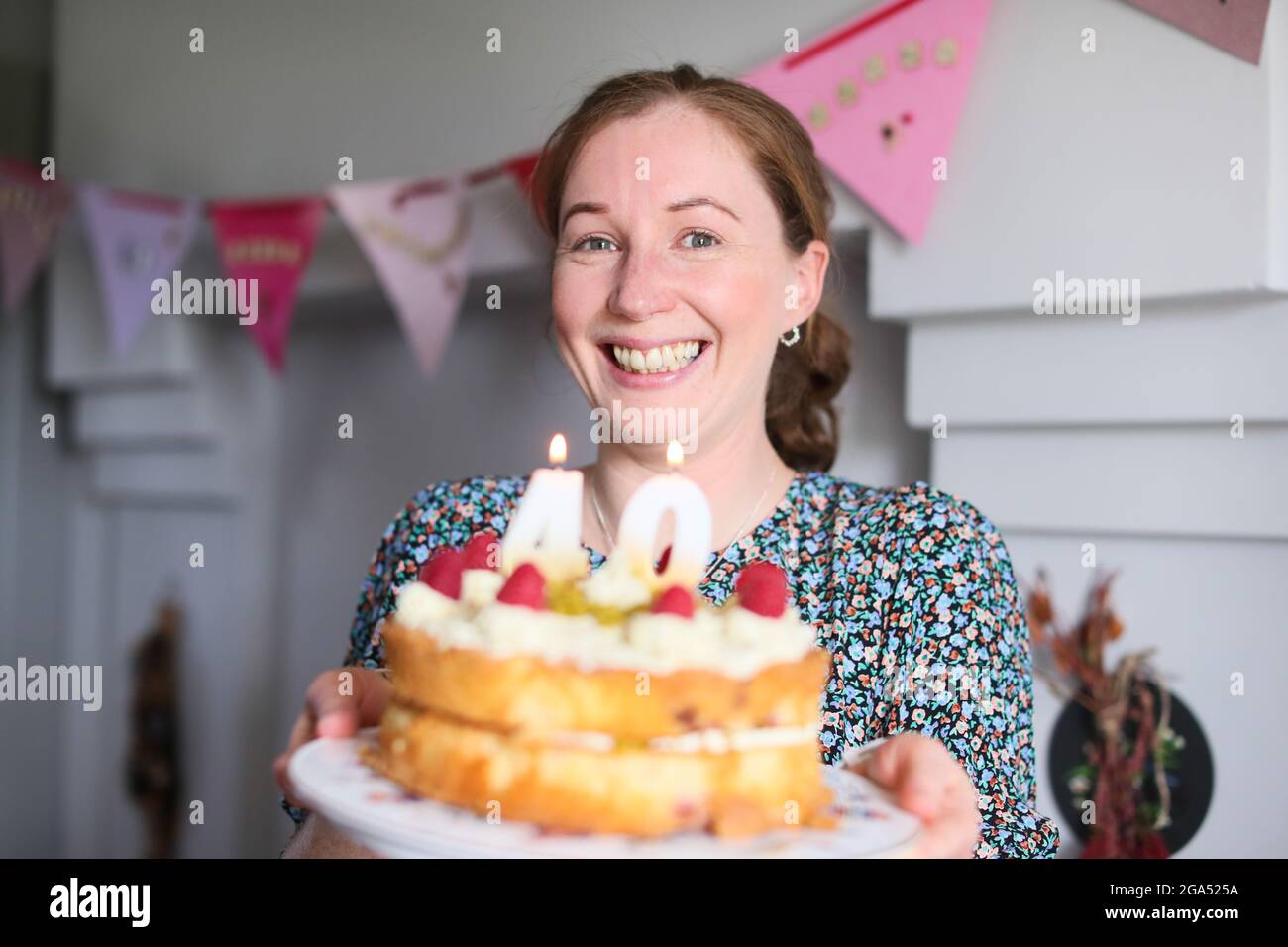 A woman celebrates her 40th birthday by blowing out the candles on her birthday cake in Armoy, County Antrim, Northern Ireland. Stock Photo