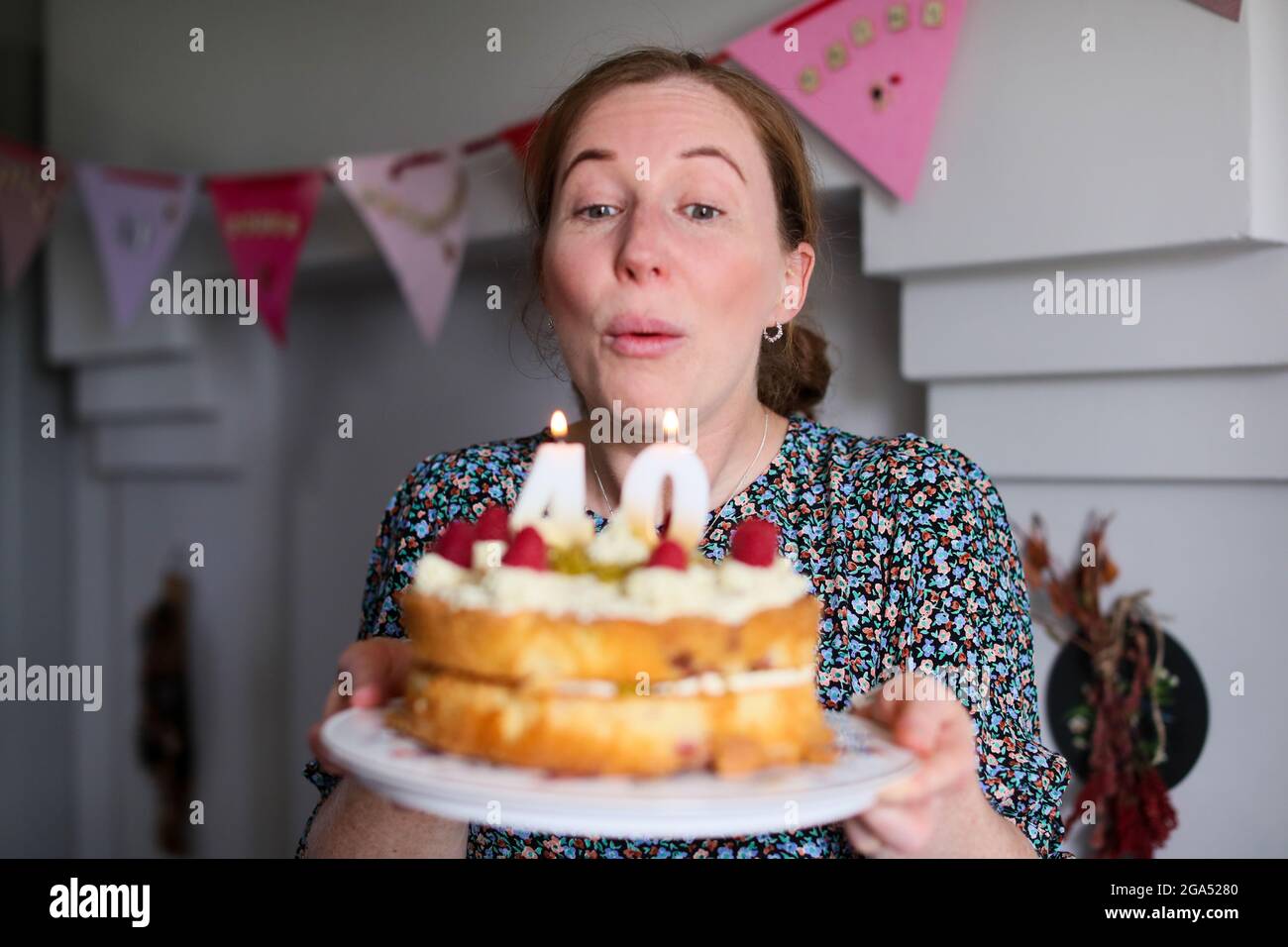 A woman celebrates her 40th birthday by blowing out the candles on her birthday cake in Armoy, County Antrim, Northern Ireland. Stock Photo