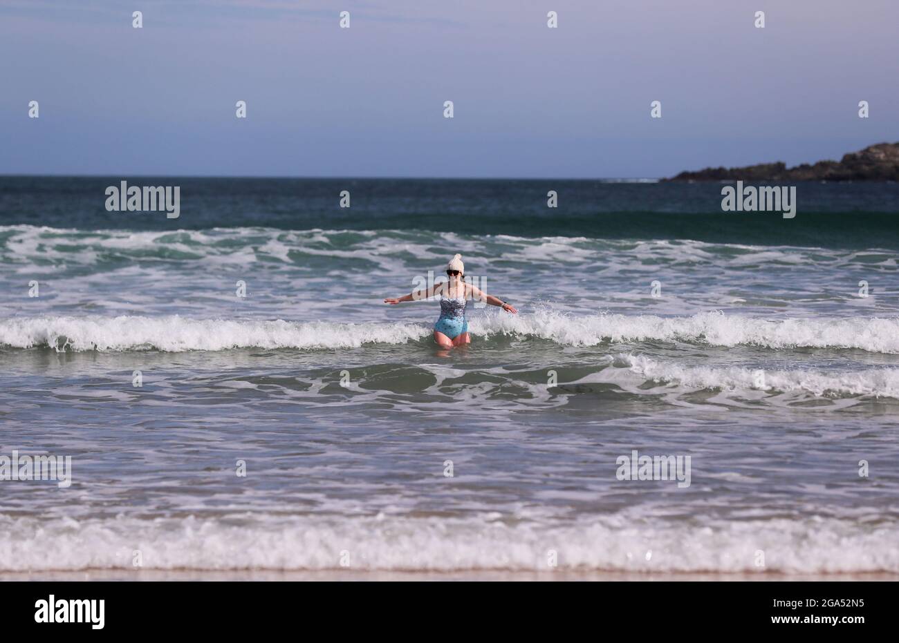 A woman on the beach at Portrush, Co. Antrim, on Northern Ireland's north coast doing open water swimming in the Atlantic Ocean. Stock Photo