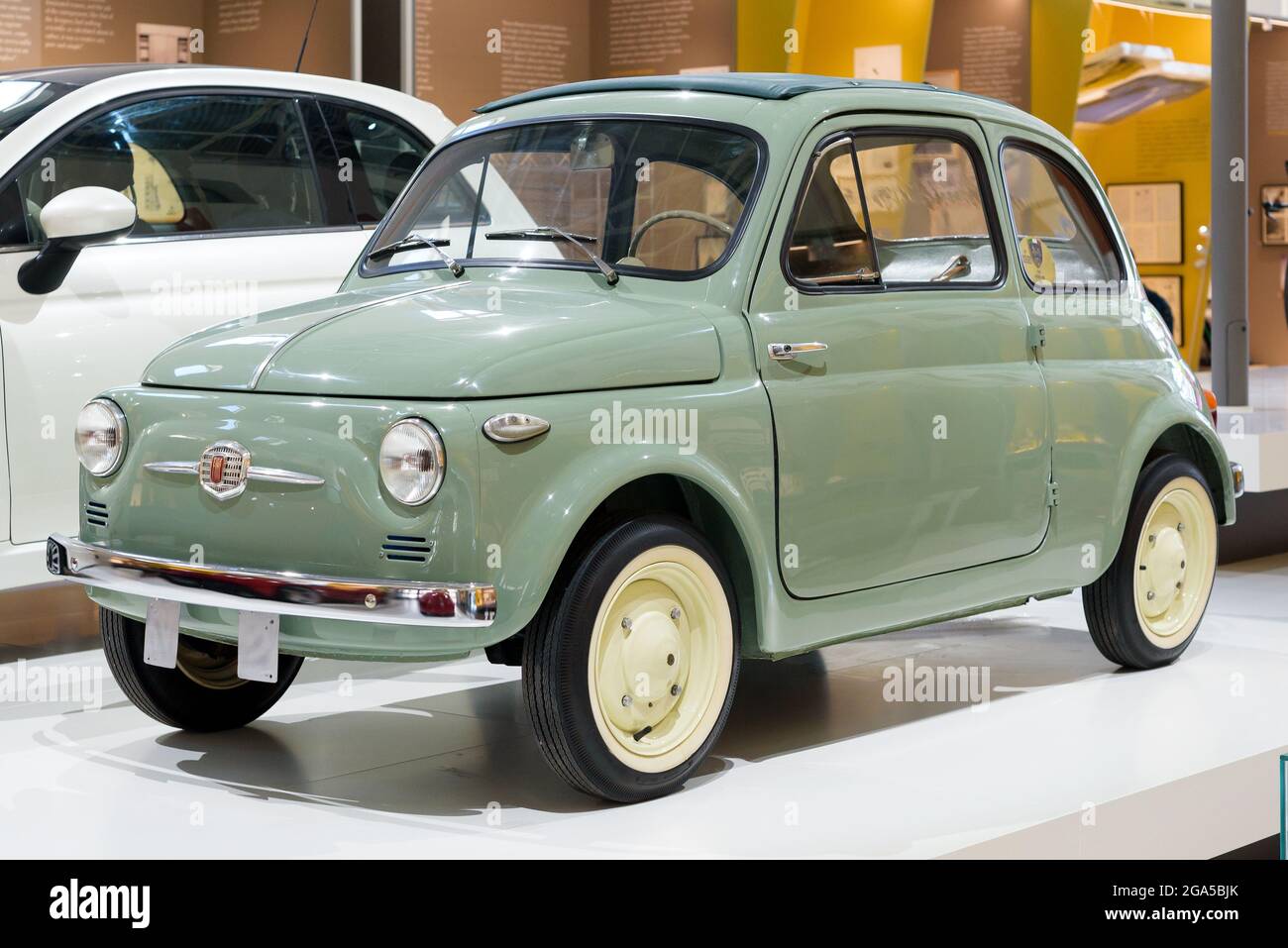 Green 1957 original Fiat 500 car on display in a motor showroom, an iconic vintage Italian vehicle in pristine condition Stock Photo
