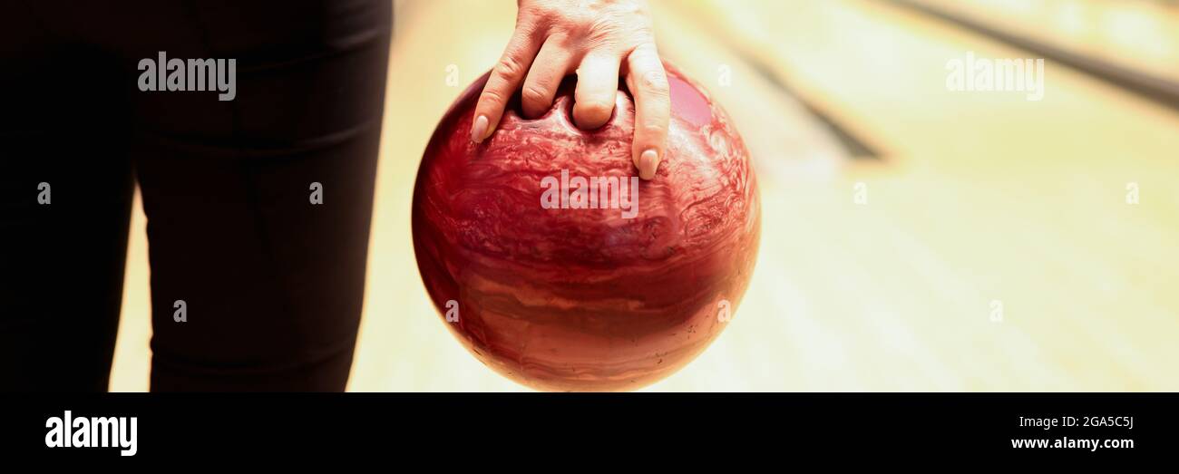 Woman throwing red bowling ball on lane closeup Stock Photo
