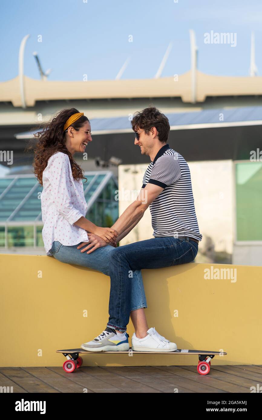 Romantic skaters couple chilling in modern city area sit look at each other with happy excited smile Stock Photo
