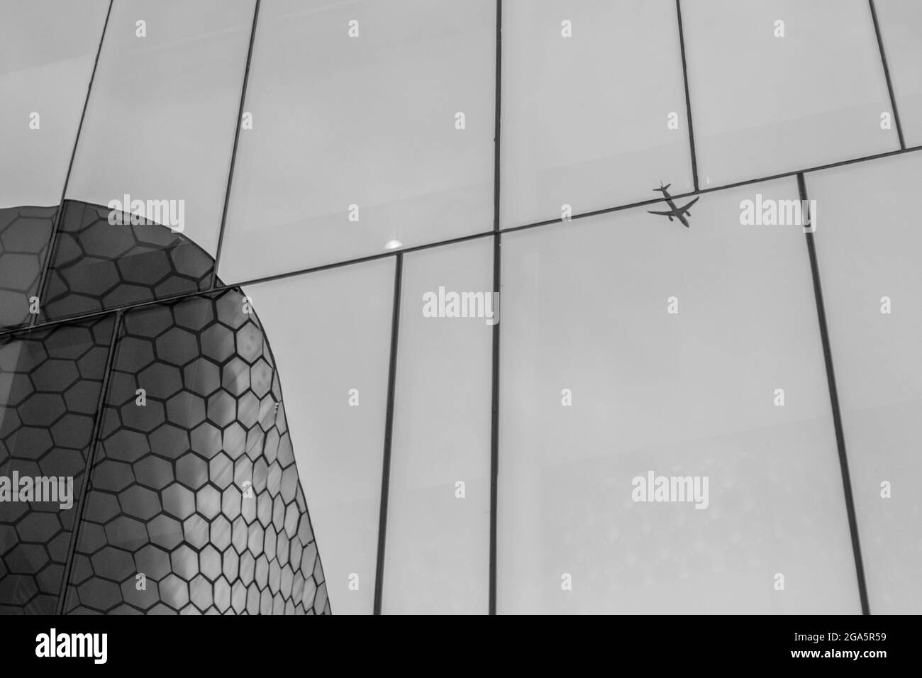 MEXICO CITY, MEXICO - Apr 23, 2019: A monochrome reflection in a glass building of the Soumaya Museum in Mexico City of a plane flying Stock Photo