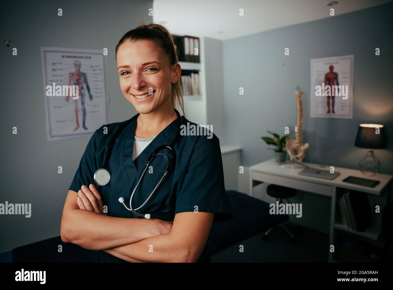Caucasian female nurse standing in clinic with with crossed arms Stock Photo