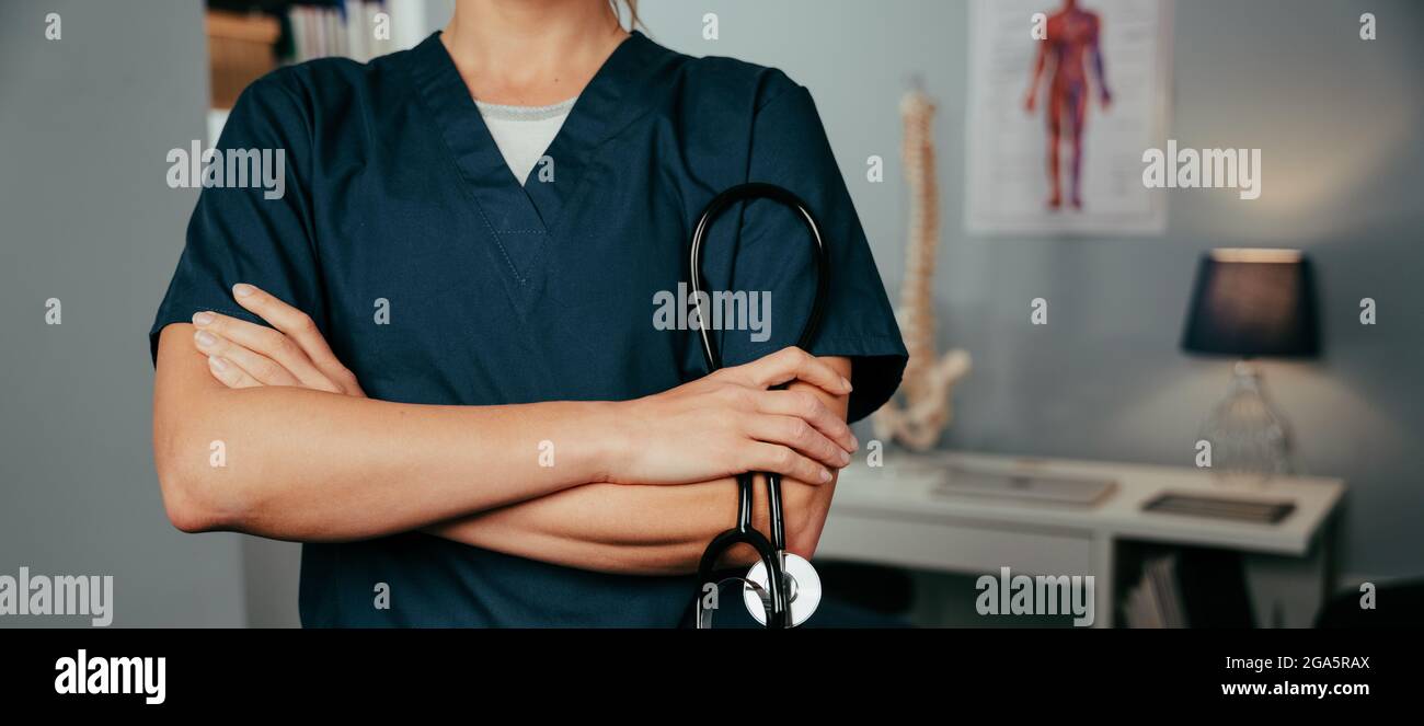 Caucasian female nurse standing in clinic with arms crossed Stock Photo