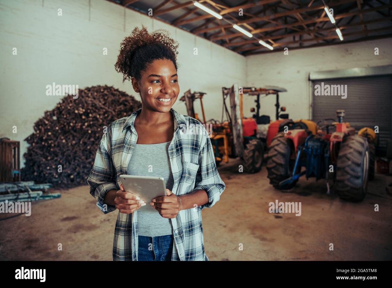 Mixed race female standing in farm store room organising layout using digital tablet  Stock Photo