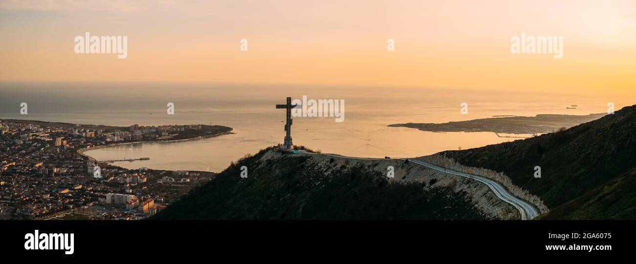 Orthodox cross on Markotkh ridge on background of Gelendzhik Bay during sunset. Stock Photo