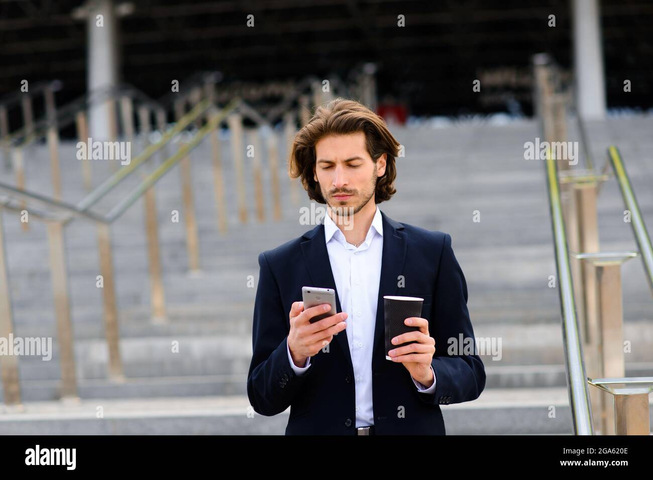 Portrait of an handsome businessman with phone, coffee cup in the city ...