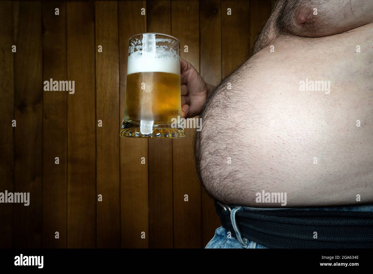 a man with a big belly with a mug of beer in his hand Stock Photo