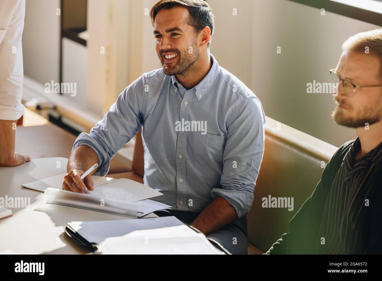 Male executive sitting in meeting. Young man paying attention to the discussion in brainstorming session at startup. Stock Photo