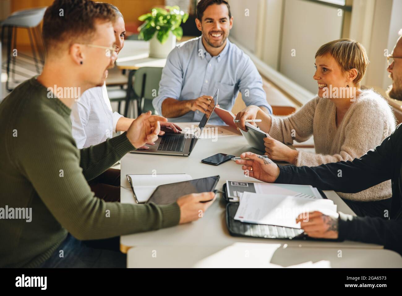 Executives in a meeting discussing on creative ideas.  Co-workers sitting at table having project meeting. Stock Photo