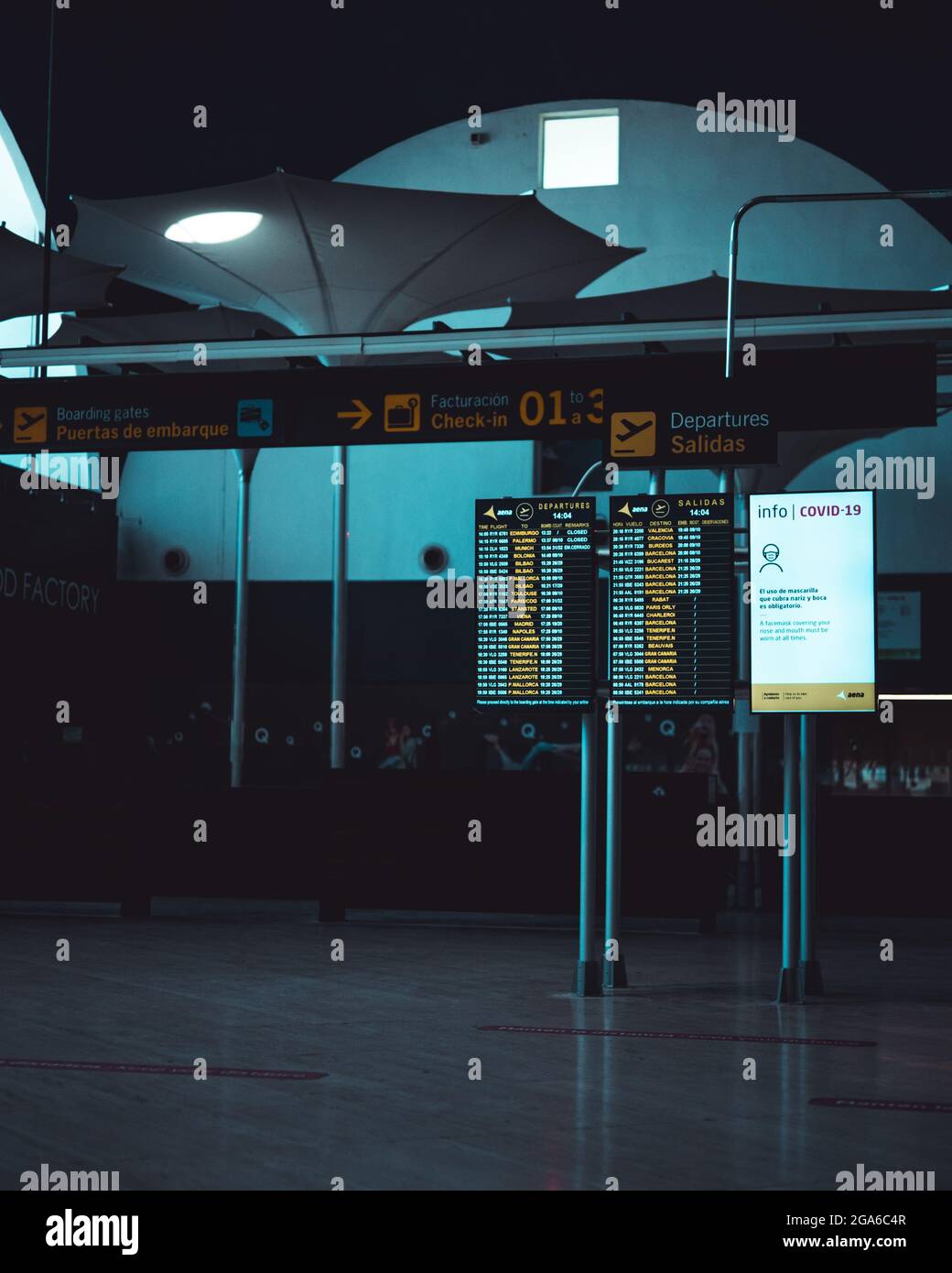 Travel, Business, Advertise - Screens showing information about the arrivals and departures of flights at an airport and a poster about covid measures Stock Photo