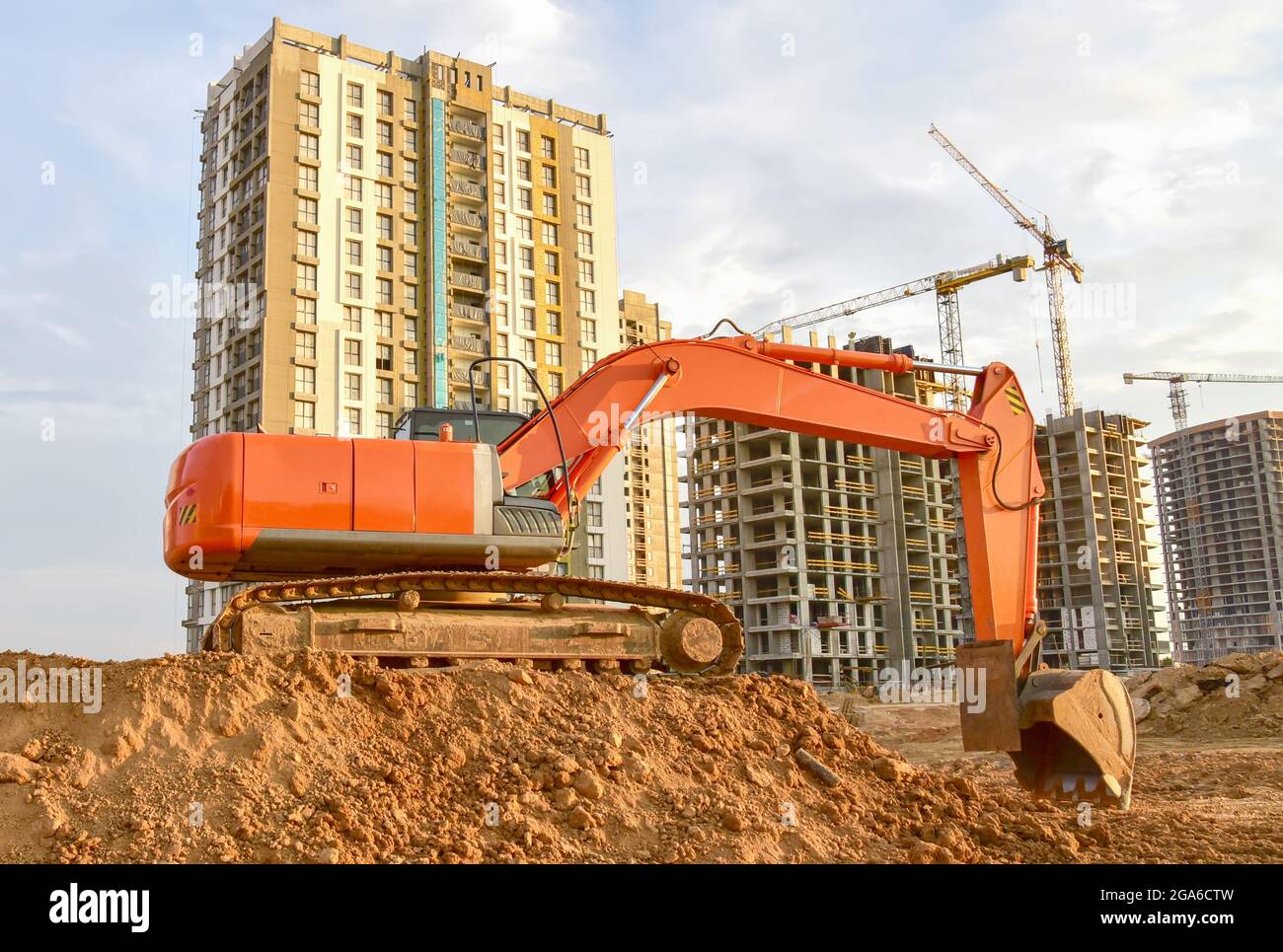 Excavator during excavation aond road construction works at construction site on sunset