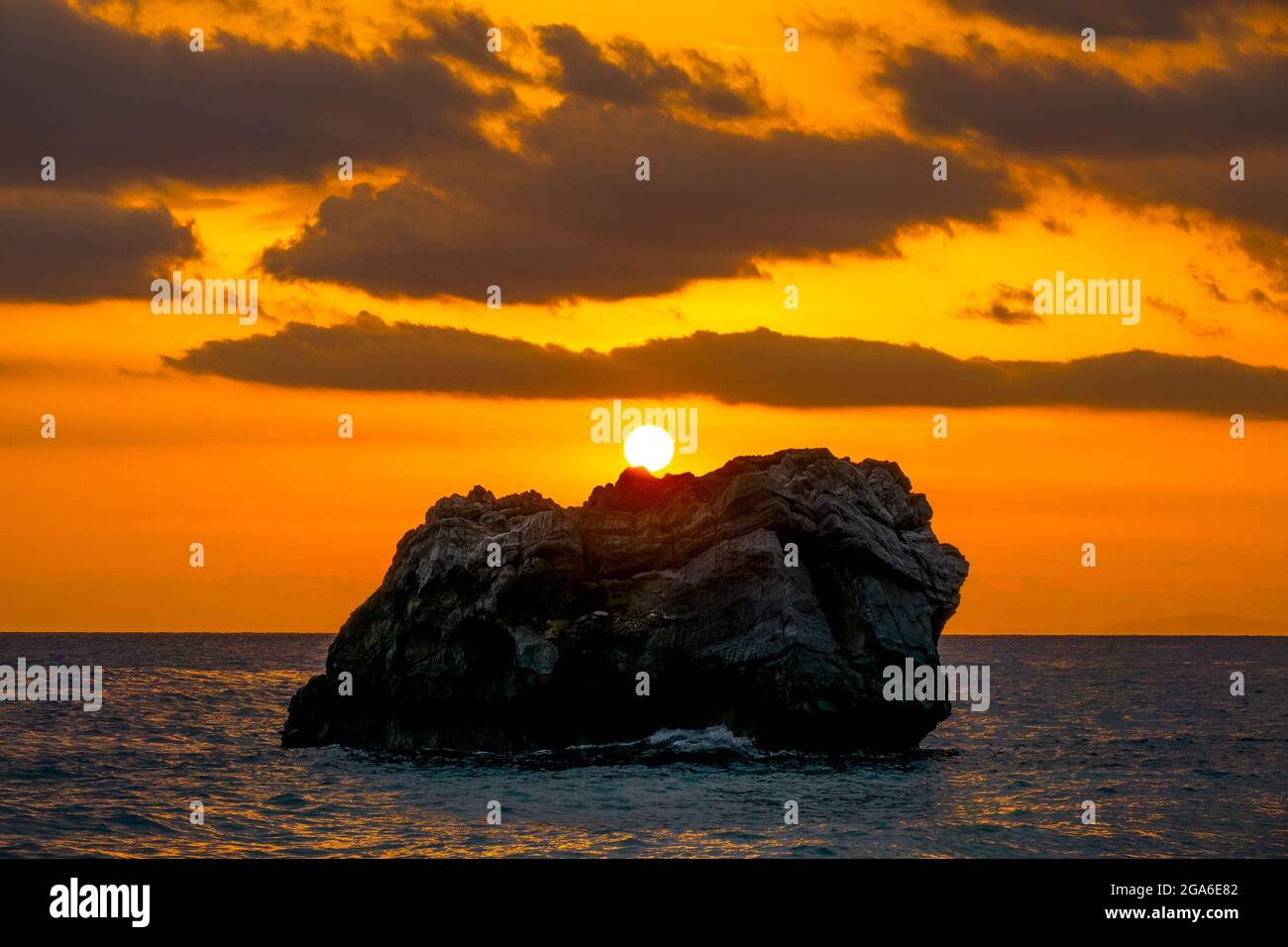 Coastal stones in the calm sea. Bright sunset colors in cloudy skies Stock Photo