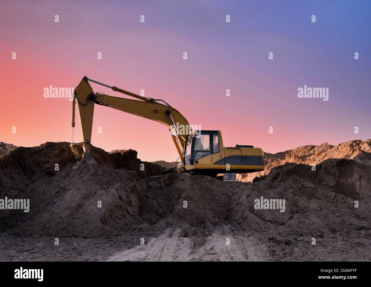 Excavator working on earthmoving at open pit mining on sunset