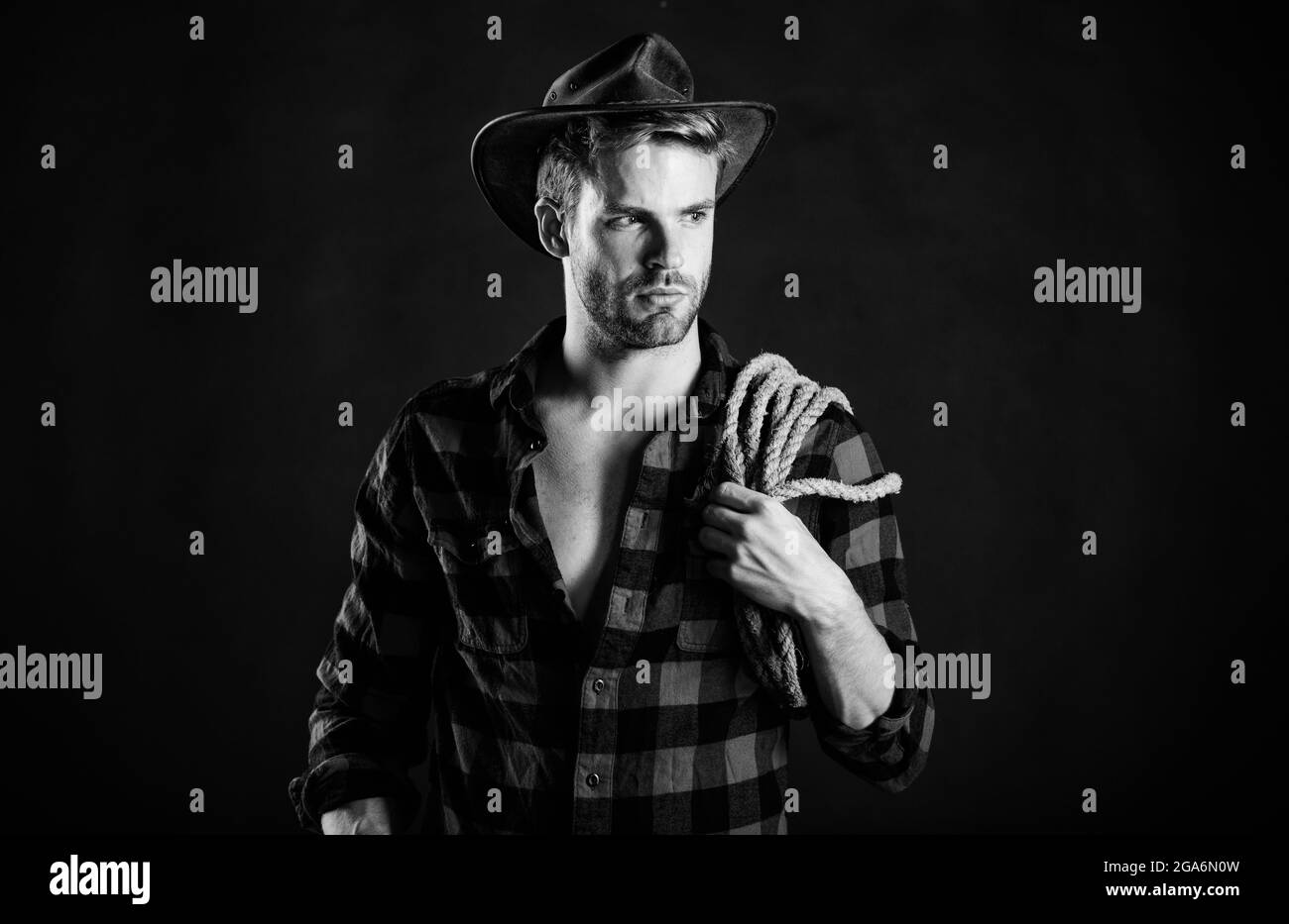 Lassoing on prairie. Man unshaven cowboy black background. Cowboy