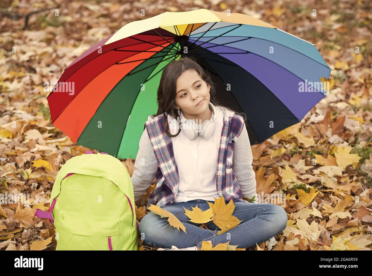 child in the rain with backpack No more rain. girl with backpack under rain protection. child relax in  autumn forest. fall leaves in park. back to school. enjoy warm seasonal  weather Stock Photo